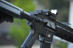 Detailed close-up of a tactical rifle with focus on the barrel and scope.